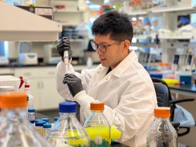 Juhong Chen in the Bioengineering & Biosensing Laboratory using a pipette to get a closer look at liquid samples.